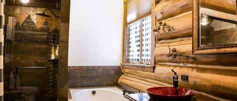 Un baño con bañera, cabina de ducha con mampara de vidrio y ventana con vistas a edificios.