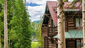 A log cabin with a balcony, surrounded by trees and a view of a valley. - Limber Pine Lodge by Cottonwood Lodging (Brighton)