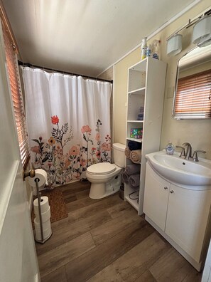 Un baño con inodoro, lavabo y cortina de ducha con motivos florales.