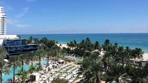 A resort with a pool, palm trees, and a view of the ocean.