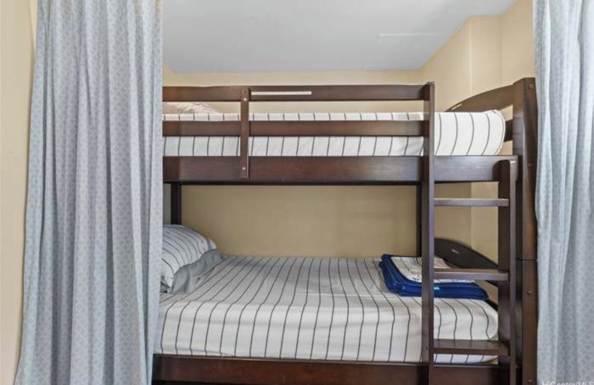 Een stapelbed met een houten frame en gestreepte beddengoed.