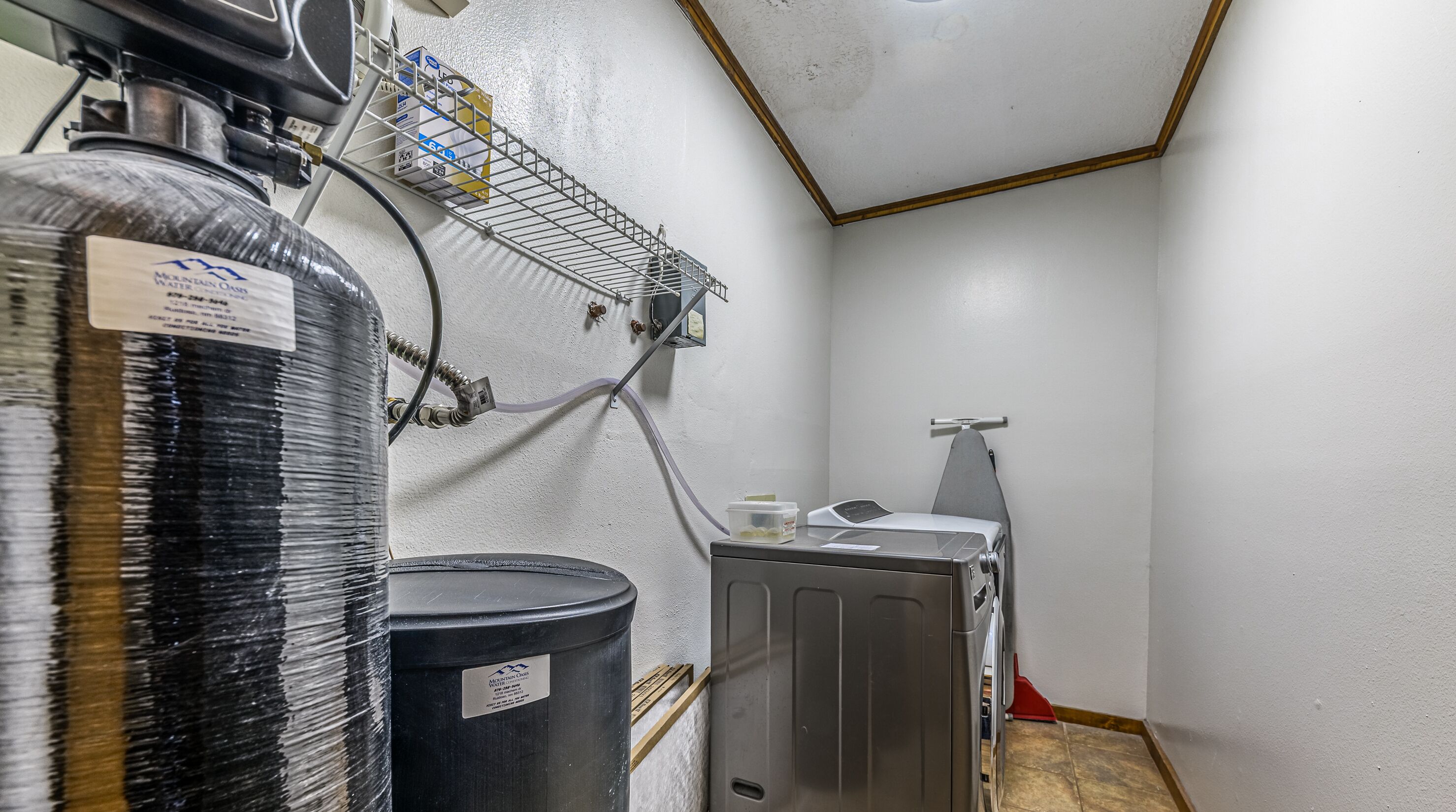 A small utility room with a water heater, a water filter, and a water pump.
