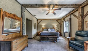 Une chambre à coucher rustique avec un plafond en bois, un grand lit, une commode et une chaise.