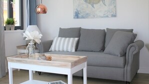 Een moderne woonkamer met een grijze bank, een witte salontafel en een schilderij van een vis aan de muur.