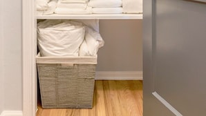 A closet with shelves holding folded towels and a basket. - Universal Hideaway  (Burbank)