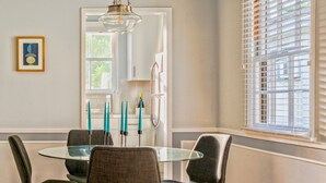 A dining area with a round glass table, four chairs, and a chandelier. - Universal Hideaway  (Burbank)