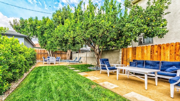 A backyard with a lawn, a wooden fence, and outdoor furniture including a table and chairs. - Universal Hideaway  (Burbank)