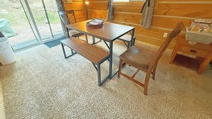 Ein gemütliches Blockhaus-Interieur mit einem Holztisch, Bänken und einem Stuhl.