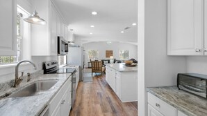 Une cuisine moderne avec des meubles blancs, un plancher en bois et un îlot central.