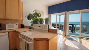Una cocina moderna con armarios de madera, microondas, estufa y plantas en macetas.