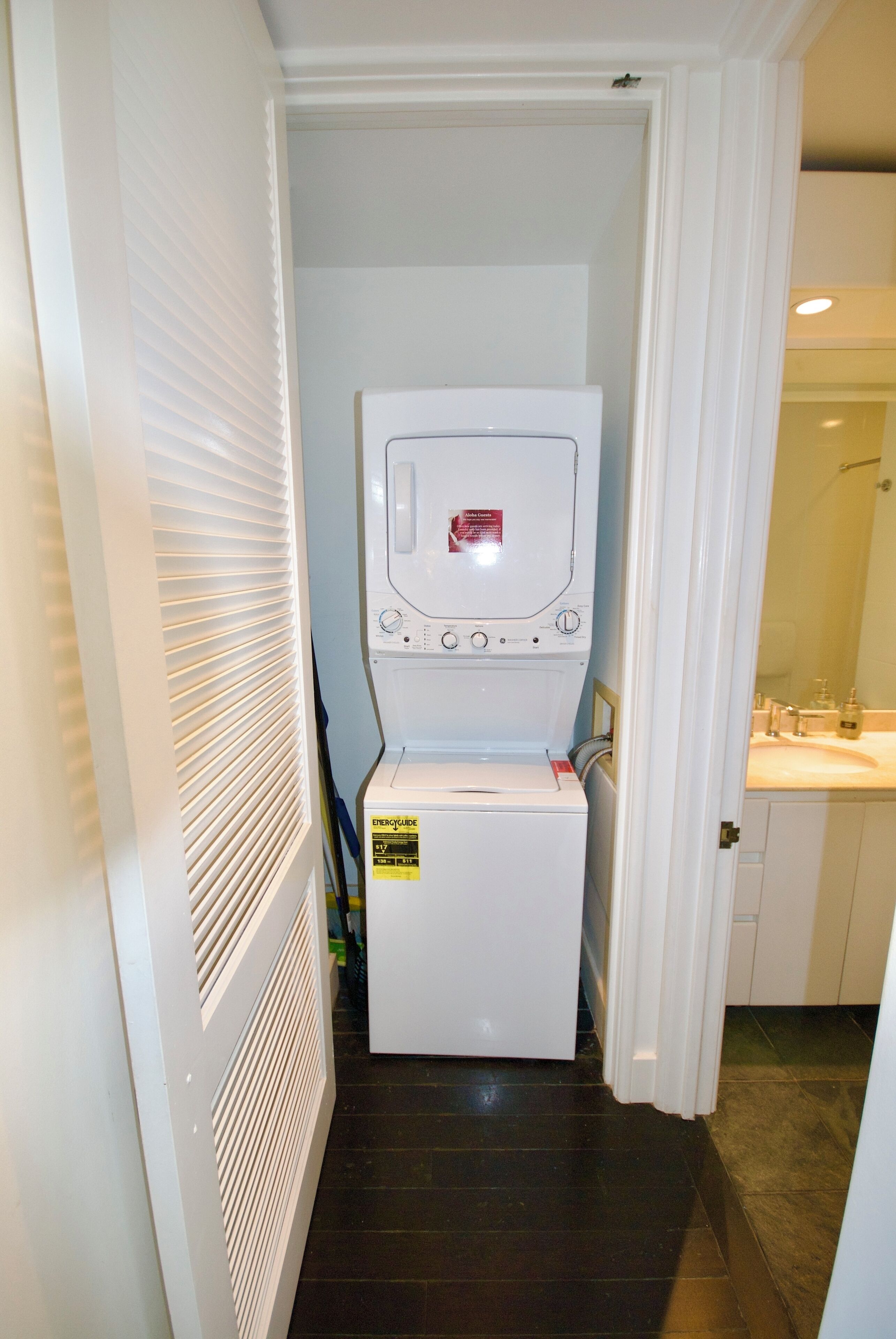 A laundry room with a front-loading washer and dryer, a white door, and a tiled floor.