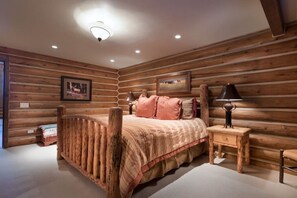 Un dormitorio de estilo cabaña de madera con una cama de madera, una mesita de noche y una lámpara.