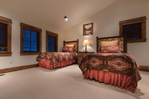 A bedroom with two beds, wooden window frames, a painting on the wall, and a lamp on a nightstand. - Teton Springs Cabin with Private Hot Tub and Air Conditioning (Victor)