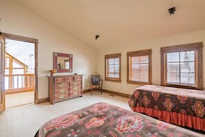 Un dormitorio con dos camas, un aparador, una silla y una ventana con persianas.