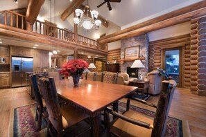 Un salón espacioso con una mesa de comedor de madera, asientos cómodos, una chimenea y vistas al exterior.