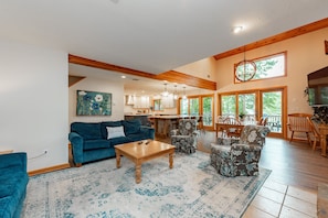 A spacious living room with a blue sofa, patterned armchairs, a wooden coffee table, and a large rug. - Deep Creek Gem w/ Dock, Fire Pit, Views & Hot Tub (Oakland)