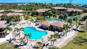 Un resort con una piscina centrale, diversi edifici per gli ospiti e un paesaggio circostante con alberi e vista sull'oceano.