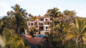 Un hôtel à plusieurs étages doté d’une piscine entourée de palmiers.
