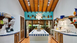 Une cuisine dotée d’un îlot central, de meubles en bois et d’un dosseret carrelé aux motifs bleus et blancs.