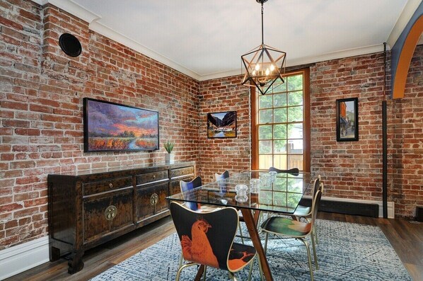 Cozy dining area with exposed brick walls, a glass-top table, and unique chairs.