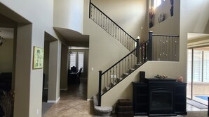 A spacious living area with a curved staircase, a fireplace, and a view of the outdoors.