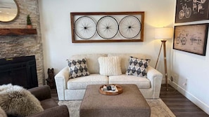A living room with a sofa, a coffee table, a fireplace, and wall art. - Updated condo & easy access to hot tub/pool (Eden)