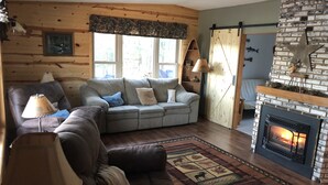 A cozy living room with a fireplace, a sofa, a chair, and a rug. - Little Muskie Retreat on Little Muskie Lake, Canoe included!   Snowmobile! (Woodruff)