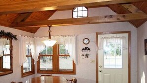 A dining area with a wooden table and chairs, a chandelier, and a door with a window. - Little Muskie Retreat on Little Muskie Lake, Canoe included!   Snowmobile! (Woodruff)