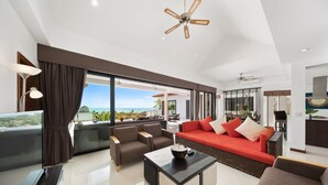 A spacious living area with a large flat-screen TV, a coffee table, and a red sofa.