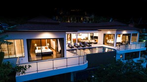 A modern two-story house with a swimming pool, large windows, and outdoor seating.