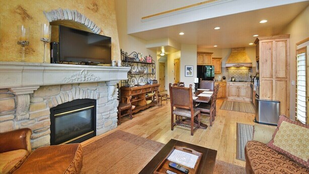A spacious living room with a stone fireplace, a television, and a dining area with wooden furniture.