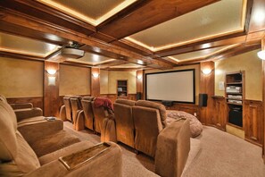 Ein Heimkinozimmer mit Holzvertäfelung, einer großen Leinwand und mehreren Sitzbereichen.