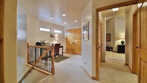 A hallway with a staircase, wooden doors, a dining area, and a lamp.