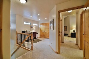 A hallway with a staircase, wooden doors, a dining area, and a lamp. - Comfy Large Townhome with private hot tub (Eden)