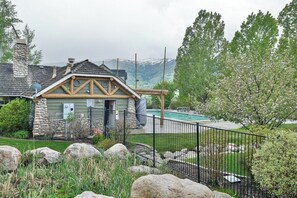A stone house with a wooden deck, a swimming pool, and a mountainous backdrop. - Comfy Large Townhome with private hot tub (Eden)
