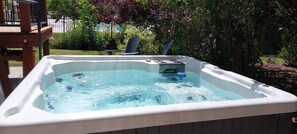 Un jacuzzi con terraza de madera y una piscina al fondo.