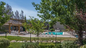 A fenced outdoor area with a pool, lounge chairs, and a covered seating area.