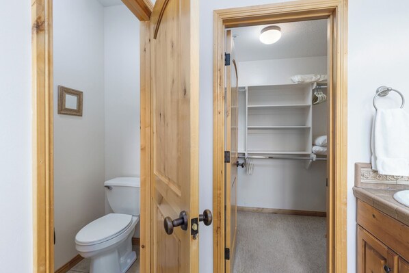 Un baño con inodoro, una puerta de madera, ducha y toallero.