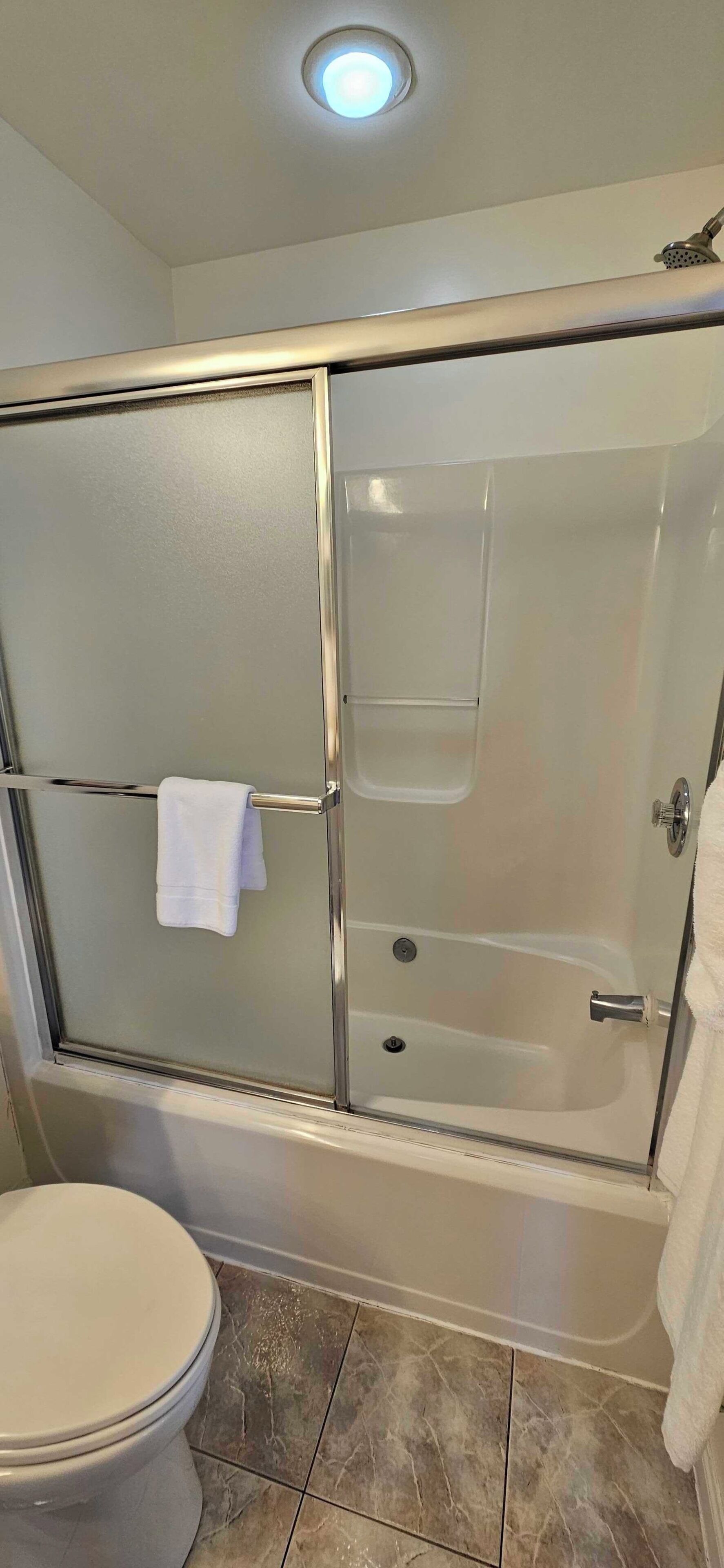 A bathroom with a glass-enclosed shower, a toilet, and a bathtub.
