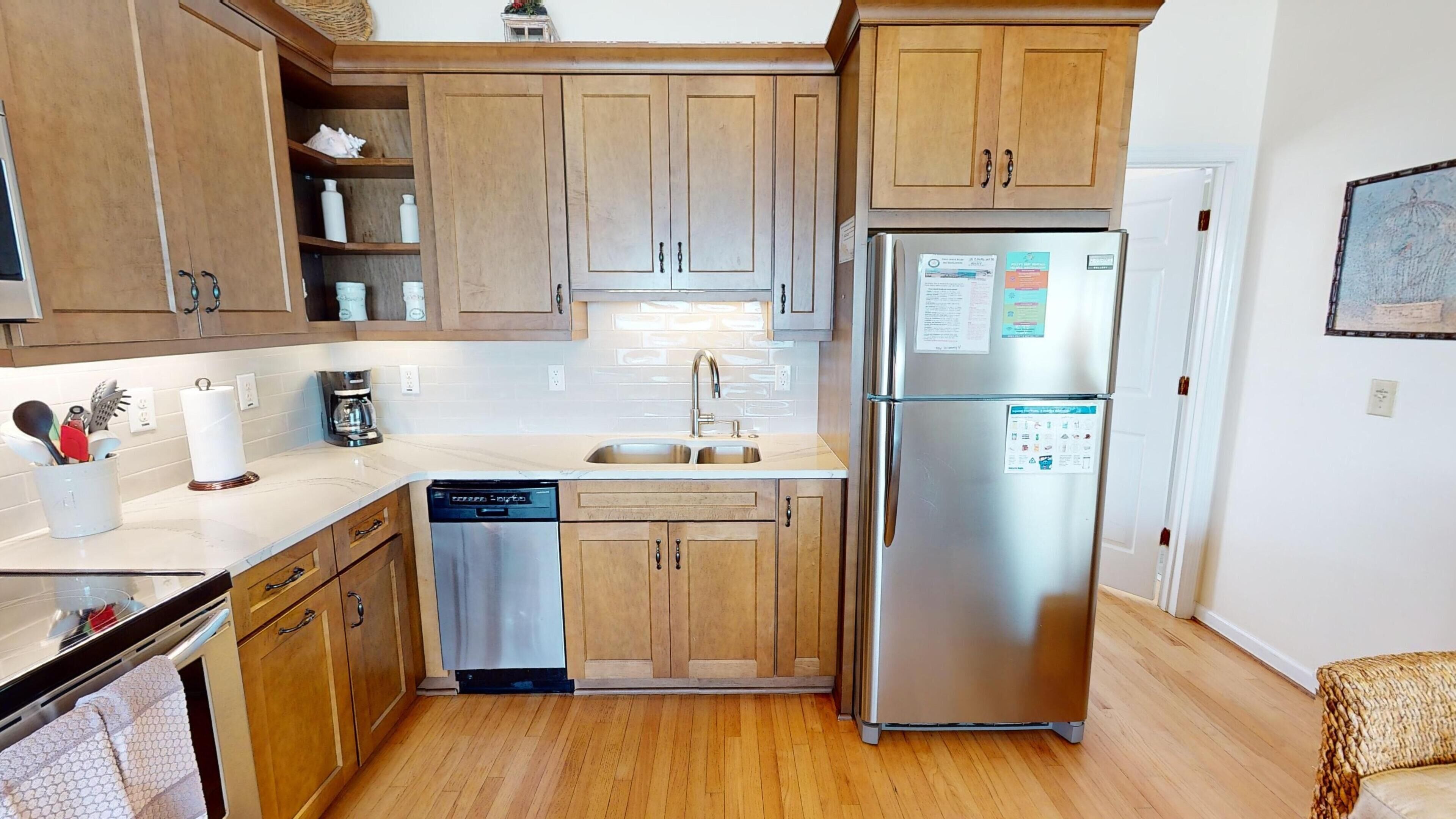A kitchen with wooden cabinets, a stainless steel refrigerator, a dishwasher, and a sink.