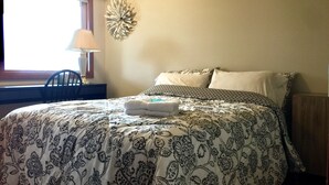A neatly made bed with patterned bedding, a bedside lamp, and a decorative wall piece. - Bellevue Retreat - Bellevue,  East of Seattle, WA (Bellevue)