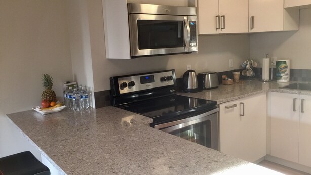 A kitchen with a stainless steel microwave, a stove, and a toaster. There are cabinets, a countertop, and a bar stool. - Bellevue Retreat - Bellevue,  East of Seattle, WA (Bellevue)