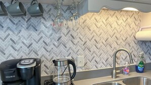 A kitchen with a herringbone tile backsplash, a coffee maker, a glass carafe, and a sink. - Historic Corner Cottage - charming 3 bedroom walking distance to waterfront (Beaufort)