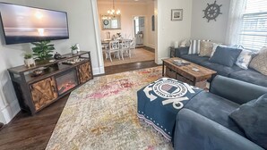 A living room with a television, a sofa, a coffee table, and a rug. - Historic Corner Cottage - charming 3 bedroom walking distance to waterfront (Beaufort)