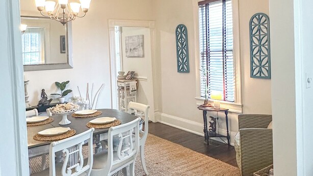 A dining area with a chandelier, a 'WELCOME' sign, and decorative wall art. - Historic Corner Cottage - charming 3 bedroom walking distance to waterfront (Beaufort)
