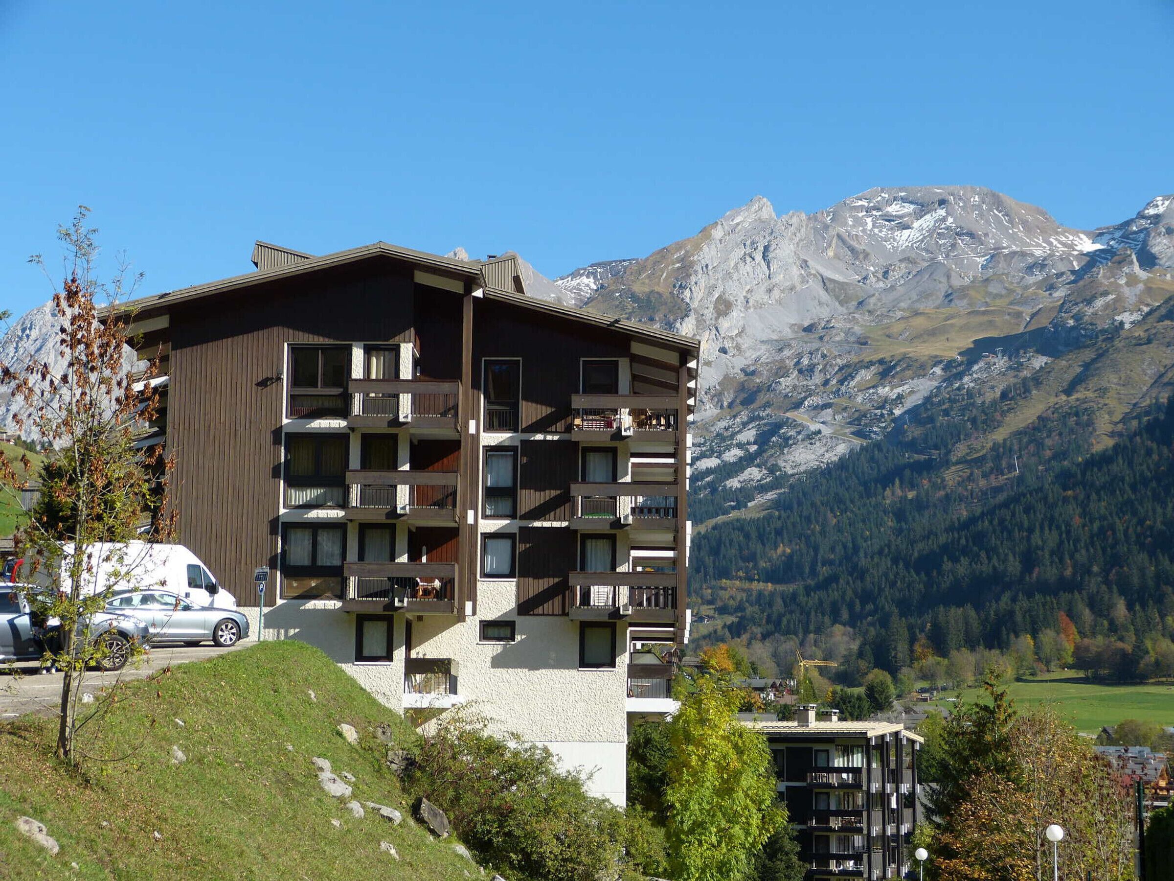 Un immeuble à plusieurs étages, doté de balcons, qui se dresse sur fond de montagnes.