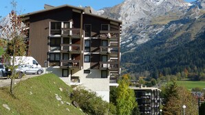 Un immeuble à plusieurs étages, doté de balcons, qui se dresse sur fond de montagnes.
