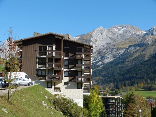 Un edificio de varios pisos con balcones, con montañas al fondo.