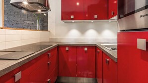 Une cuisine moderne avec des meubles de couleur rouge, une hotte de cuisine en acier inoxydable et un four encastré.