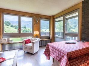 Una habitación con cama, silla, mesa y ventanas amplias que ofrecen vistas a la montaña.
